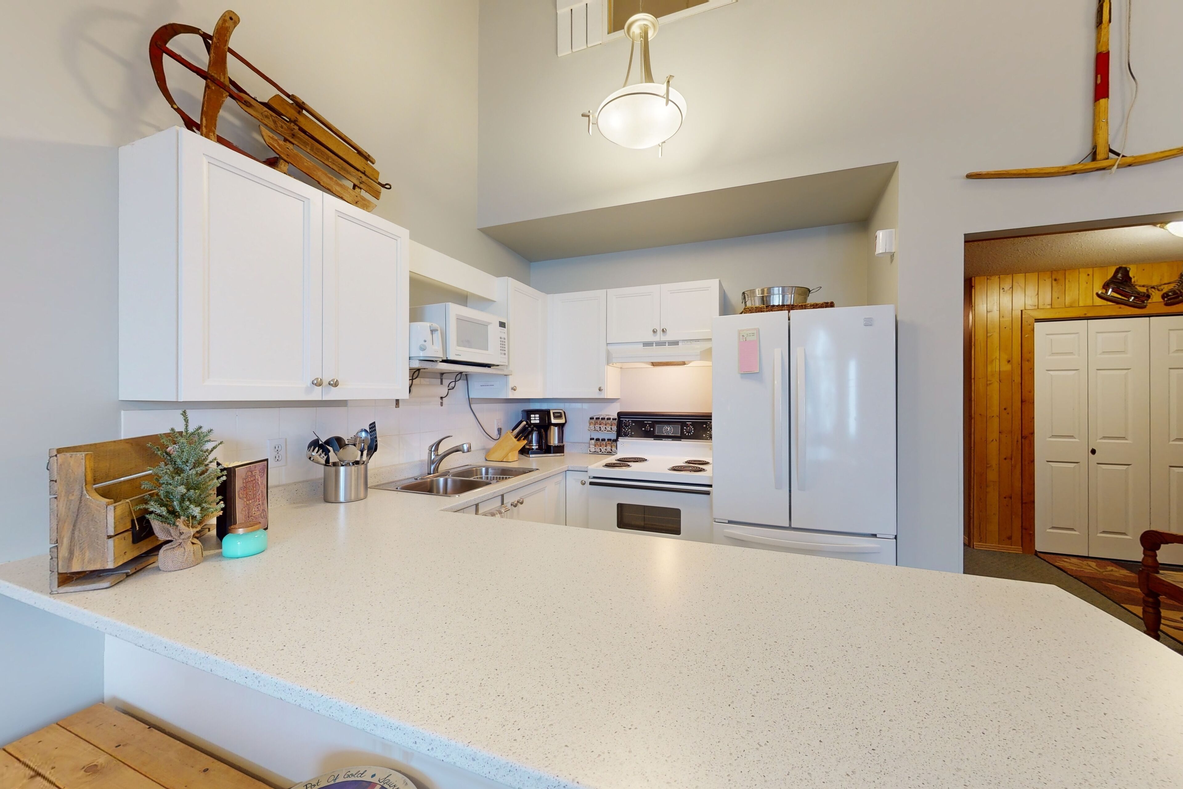 A modern kitchen with white cabinetry, a large island, a microwave, a stove, and a refrigerator.