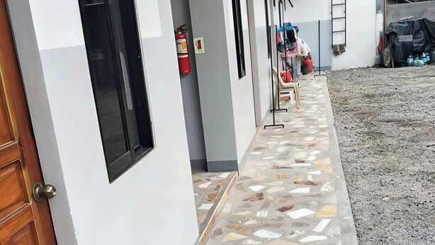 Un pasillo con piso de baldosas, una puerta de madera y un extintor.