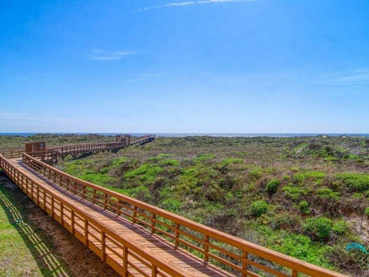 A wooden boardwalk extending through a natural landscape.