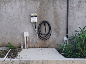 Un cuadro eléctrico exterior con un cable de alimentación y un cable enrollado en el suelo.