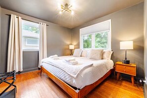 Une chambre à coucher avec un lit, des tables de chevet, une fenêtre et un luminaire au plafond.
