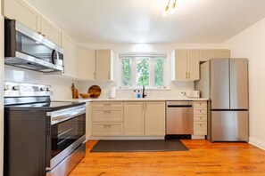 Una cocina moderna con electrodomésticos de acero inoxidable, armarios de madera y un ventanal grande.