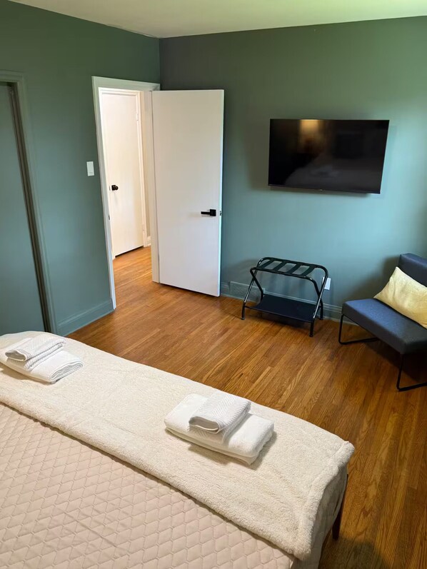 Une chambre d’hôtel avec un lit, une télévision, une porte et un petit coin salon.