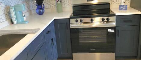 A kitchen with white cabinets, a stainless steel stove, a microwave, and a coffee maker.