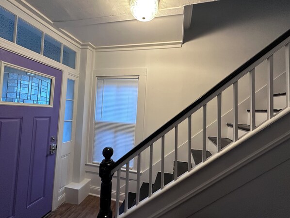 A staircase with a handrail, a purple door, and a window with blinds. - Entire House in Cambridge (Cambridge)
