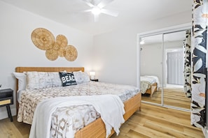 Ein Schlafzimmer mit einem hölzernen Bett, einem Nachttisch, einer wandmontierten runden Leuchte und einer Schiebetür zu einem weiteren Raum.