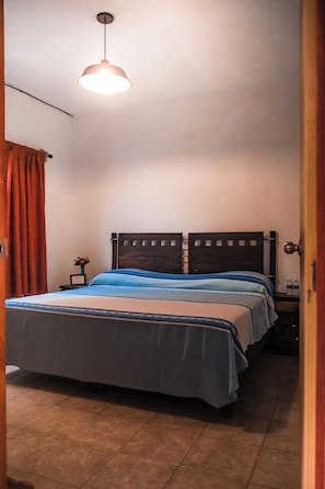 A bedroom with a bed, a nightstand, a lamp, and a door. - hospedaje casa teotleco (Tepoztlán)
