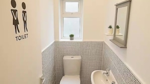 Ein kleines, modernes Badezimmer mit Toilette, Waschbecken und Fenster.