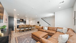 Ein modernes Wohnzimmer mit einer Eckcouch, einem Essbereich und einer Küche im Hintergrund.