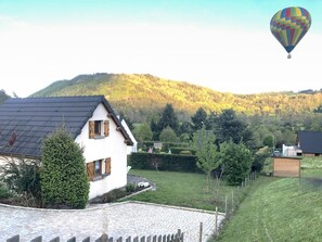 Ein Haus mit geneigtem Dach, befestigter Auffahrt und umzäunter Garten.