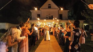 A wedding ceremony with guests holding sparklers in front of a large building. - 85Ten Hotel and Events  (Port Austin)