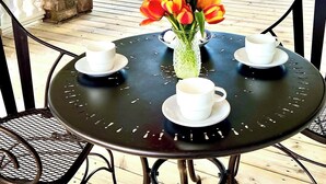A covered outdoor seating area with a table, chairs, and a vase of flowers. - 85Ten Hotel and Events  (Port Austin)