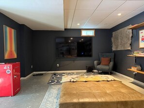 Ein modernes Zimmer mit einem großen Fenster, einem roten Kühlschrank, einem grauen Sofa und einem gemusterten Teppich.