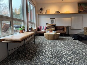 Ein Wohnzimmer mit einer Couch, einem runden Couchtisch, einer Bank und einem gemusterten Teppich.