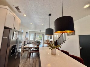 Una cucina moderna con elettrodomestici in acciaio inossidabile, un'area pranzo con tavolo bianco e una scala che conduce a un altro livello.