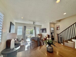 A spacious living room with a wooden dining table, a sofa, and a staircase.