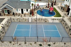 A tennis court with a pool and a building with a sloped roof. - Athlete's Retreat | Pool, Hot Tub, Pet Friendly (Washington)