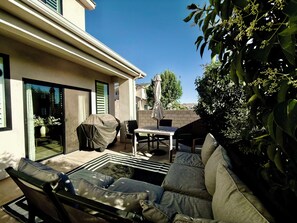 A patio with outdoor furniture, a covered grill, and a view of the neighborhood.