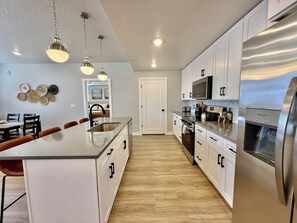 Uma cozinha moderna com armários brancos, eletrodomésticos de aço inoxidável e uma ilha central.