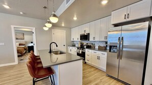 A modern kitchen with a central island, stainless steel appliances, and white cabinetry.