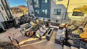 A modern outdoor seating area with a pool, surrounded by a metal fence, and a view of a mountain in the background.