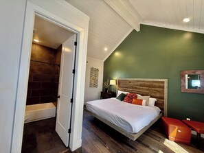 A bedroom with a wooden bed, a nightstand, a bedside table, and a green wall.
