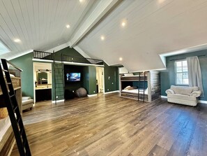 Un loft espacioso con techo alto, piso de madera, televisor empotrado y una zona de estar acogedora.