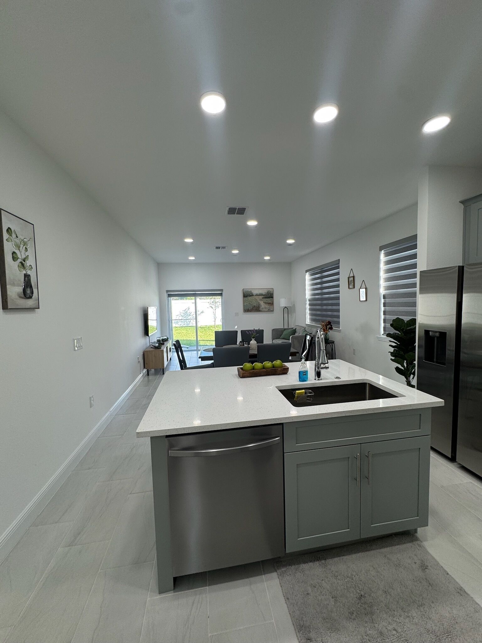 A modern kitchen with a central island, stainless steel appliances, and recessed ceiling lighting.