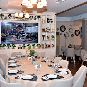Un comedor con televisor, varios relojes y una variedad de objetos decorativos en estantes.