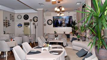 Un comedor moderno con mesas redondas, sillas y una pantalla de televisión.