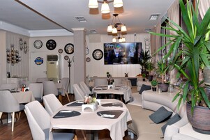 Un comedor moderno con mesas redondas, sillas y una pantalla de televisión.