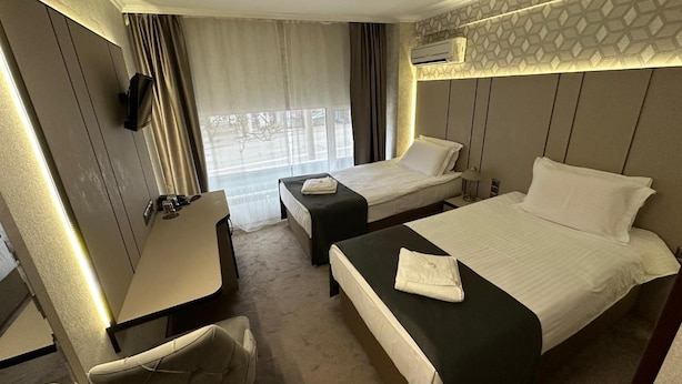 A hotel room with two beds, a desk, a chair, and an air conditioning unit. - Hotel Cosmos (Ruse)
