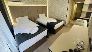 A hotel room with two beds, a desk, a chair, and a minibar. - Hotel Cosmos (Ruse)