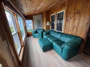 Ein Zimmer mit Holzwänden, einem teppichartigen Salonsessel in Türkis und einer Lampe.