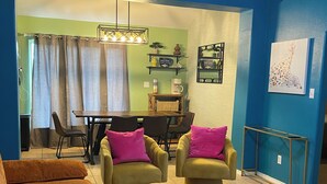 A living room with a ceiling fan, a dining area with a table and chairs, and a blue wall with a painting. - Perfect 3-bedroom house with AC in welcoming Harlingen (Harlingen)
