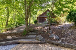 Eine Holzhütte, umgeben von Bäumen, mit einem Kiesweg, der dorthin führt.
