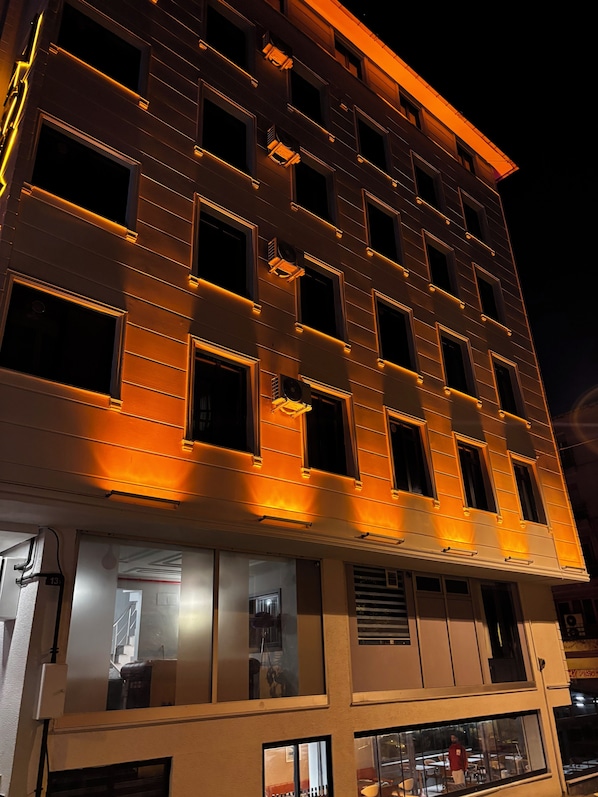 Un hotel de varios pisos con ventanas iluminadas y un restaurante en la planta baja.