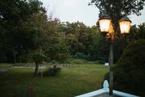 Een tuin met een pad, bomen en een lantaarnpaal.