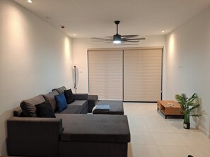 Ein modernes Wohnzimmer mit einem grauen Sofa, einem Deckenventilator und einer Schiebetür.