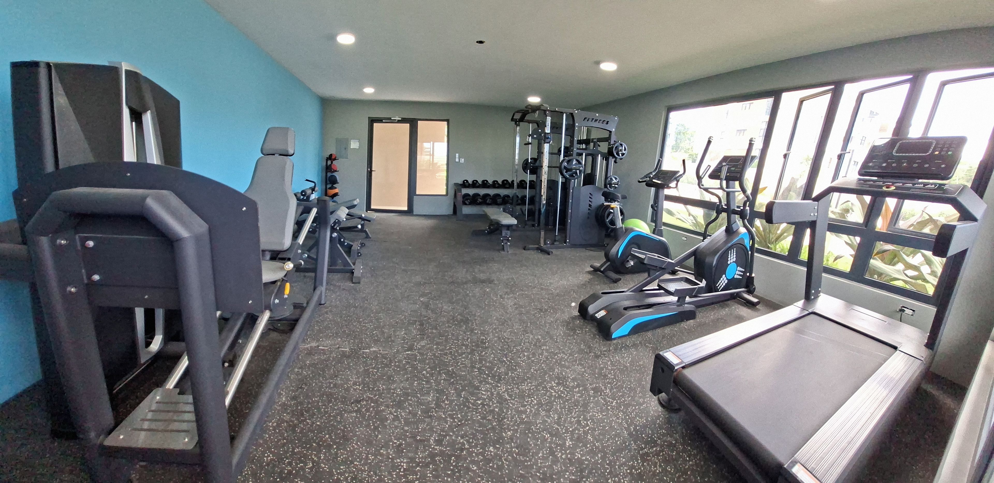 Ein Fitnessstudio mit Laufbändern, Kraftgeräten und Kurzhanteln.