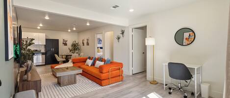 A modern living room with a sofa, coffee table, and a desk with a chair.