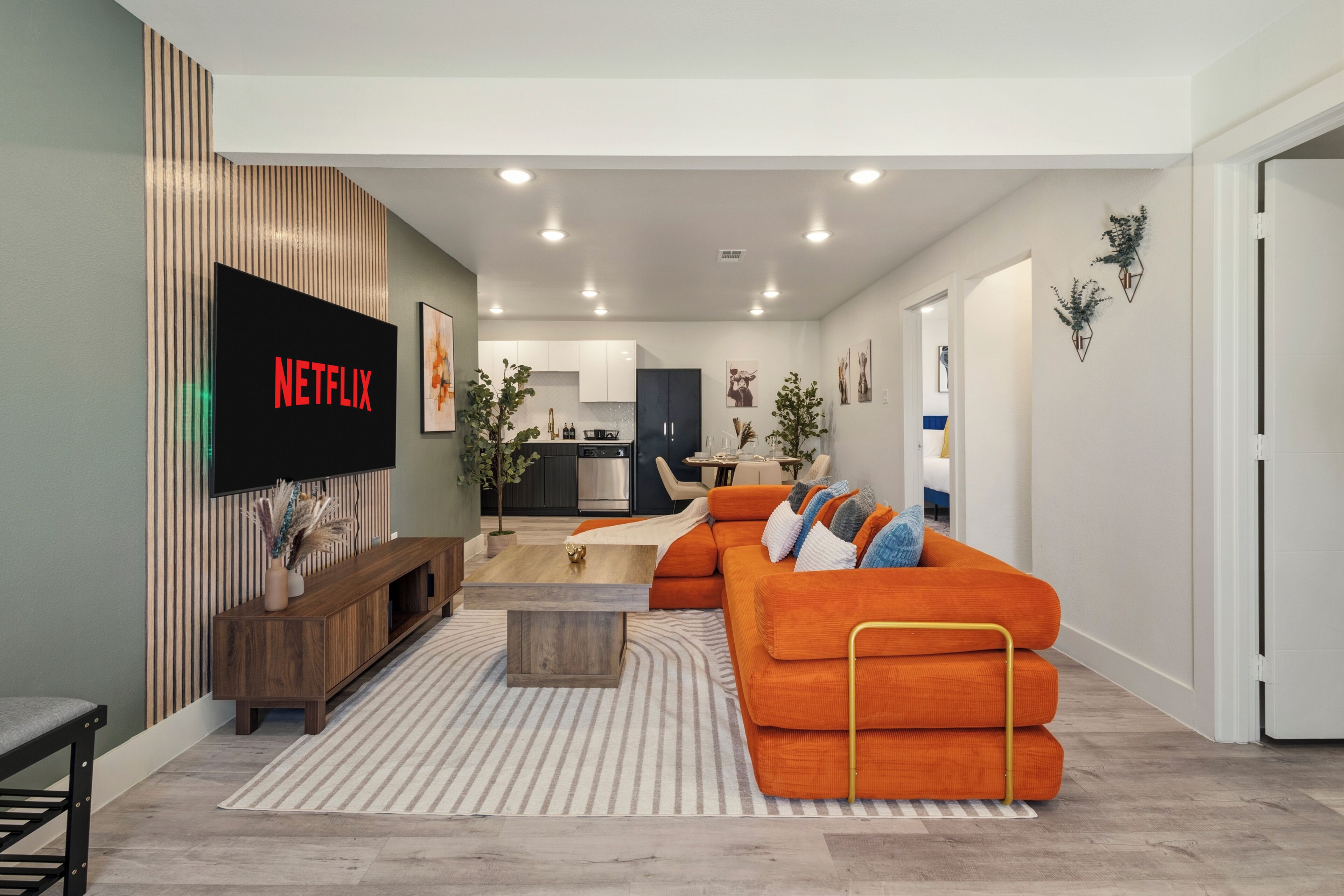 Una sala de estar moderna con un sofá, una mesa de centro y un televisor montado en la pared.
