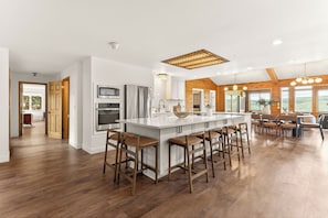A spacious kitchen with a large island, wooden accents, and a view of the outdoors.