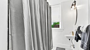 Ein Badezimmer mit Duschvorhang, Waschbecken und Handtüchern.
