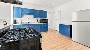 Eine Küche mit blauen Schränken, einem Edelstahlkühlschrank, einer Mikrowelle und einem Gasherd.