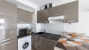 Une cuisine moderne équipée d’un lave-linge intégré, d’un four à micro-ondes et d’un évier.