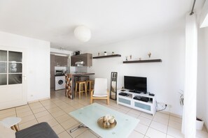 A modern living room with a dining area, a kitchen, and a TV. - L'Appartement des Pyrénées avec terrasse - Welkeys (Anglet)