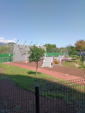Un parque infantil con un letrero que dice 'Pet Lovers', un pequeño árbol y un área cercada.