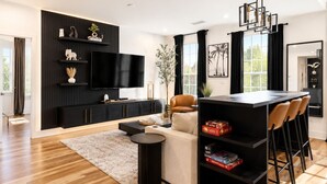 A modern living room with a black entertainment unit, a flat-screen TV, a sofa, a coffee table, and a dining area with bar stools. - Midnight Luxe Suite with Walkable Areas, Keyless Check-in and Free Parking (Atlanta)