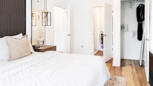 Een slaapkamer met een bed, nachtkastje, spiegel en kledingkast.
